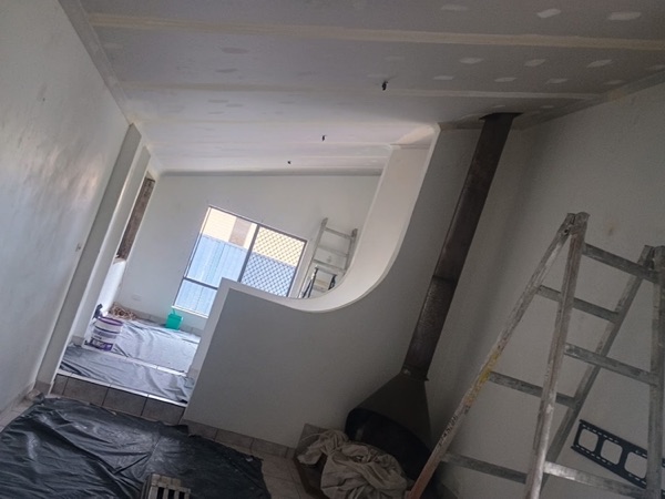 A curved plastered bulkhead and hallway opening with drop sheets on the floor