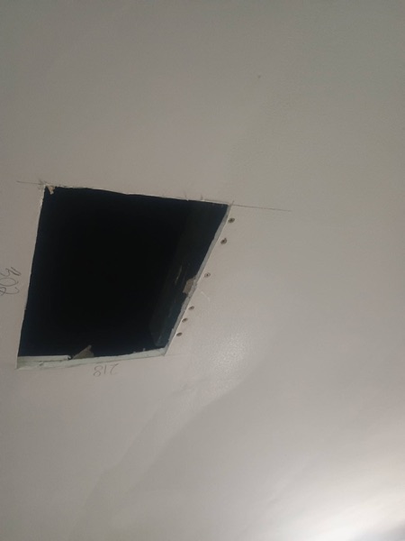 A rectangular opening cut into a ceiling with the edges squared off
