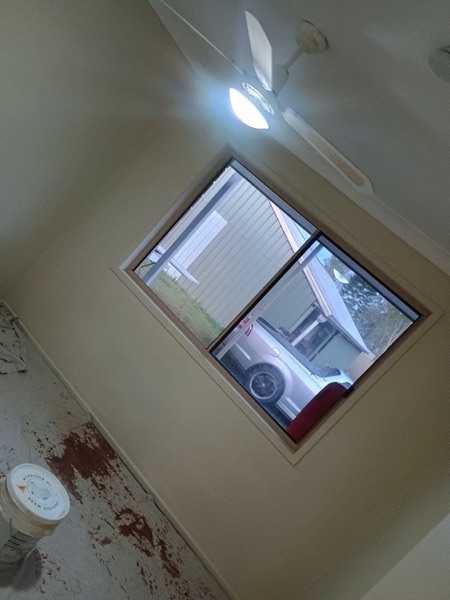 A window opening in a wall with fresh plaster patched around the frame