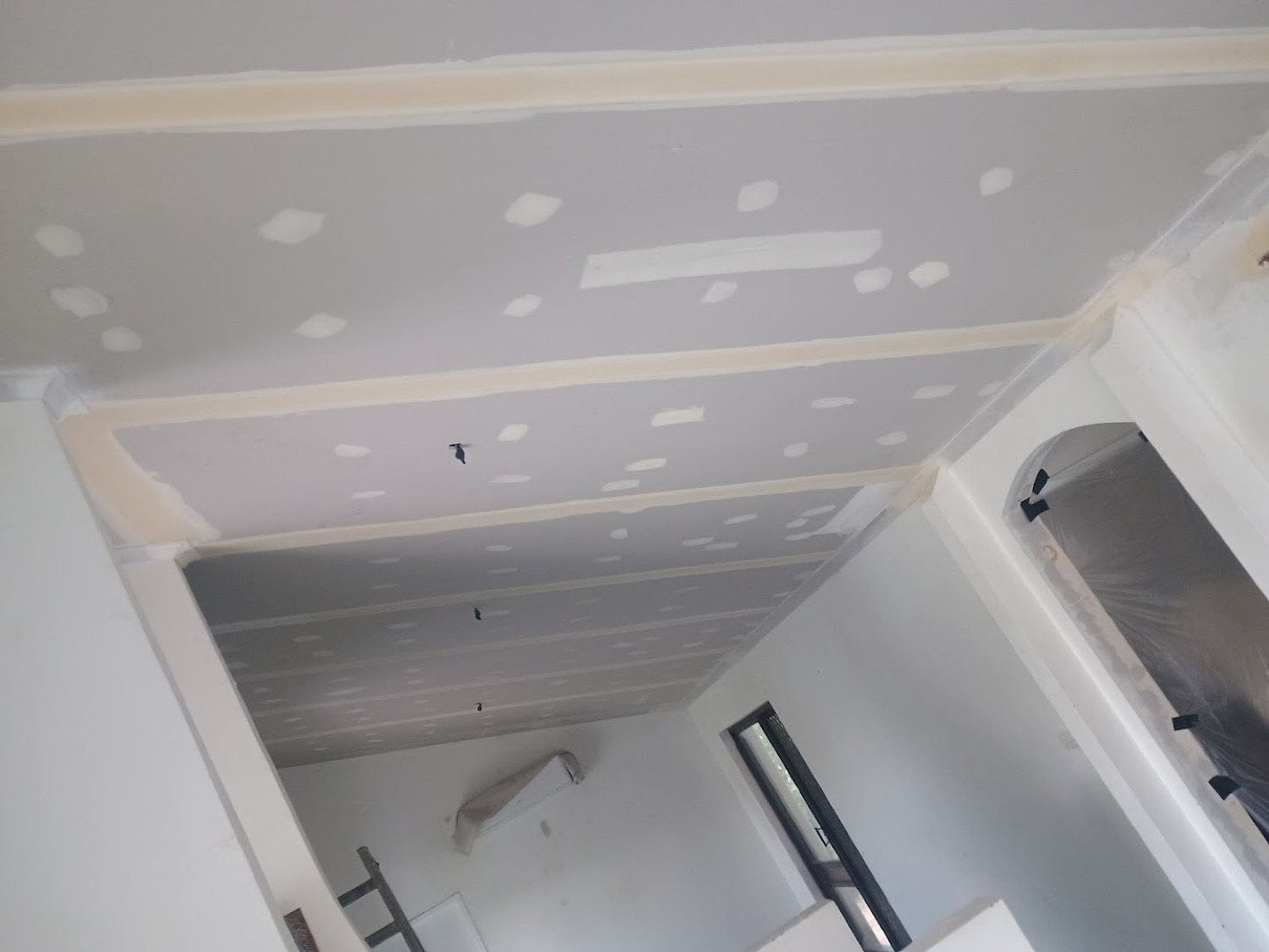 A bathroom ceiling being set, with a ladder standing under the work