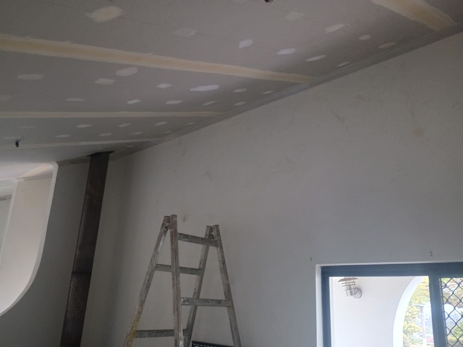 A set wall beside a window with a ladder resting against it