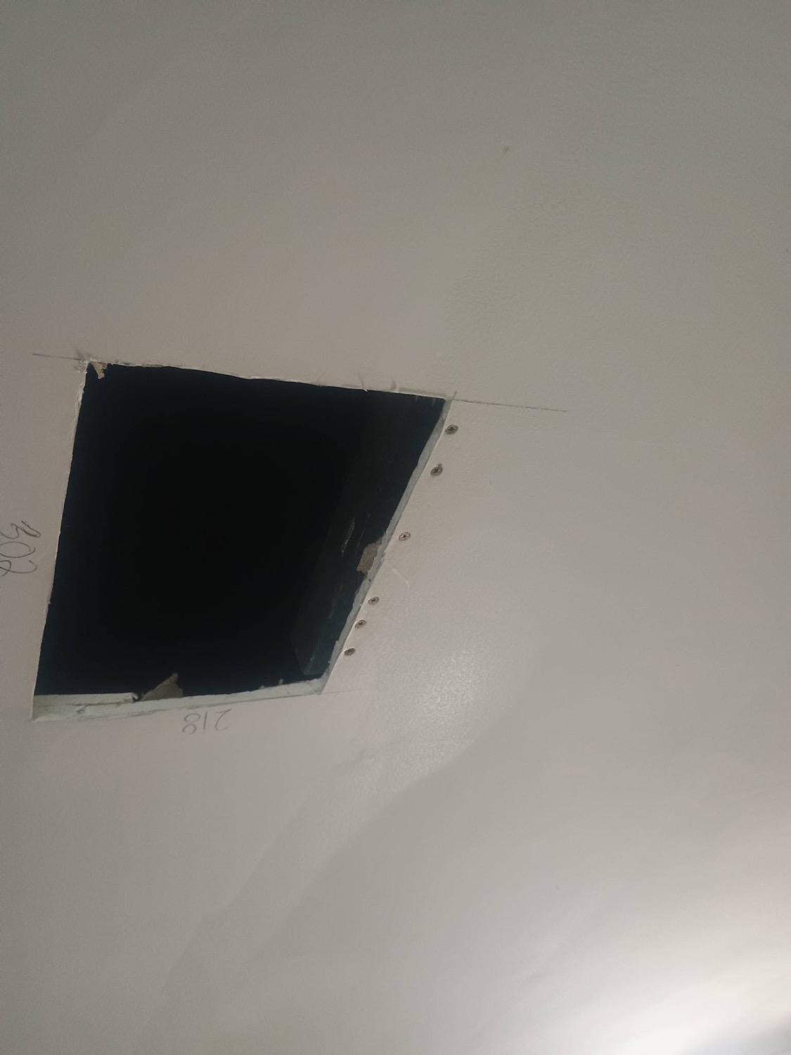 A rectangular opening cut into a ceiling with the edges squared off