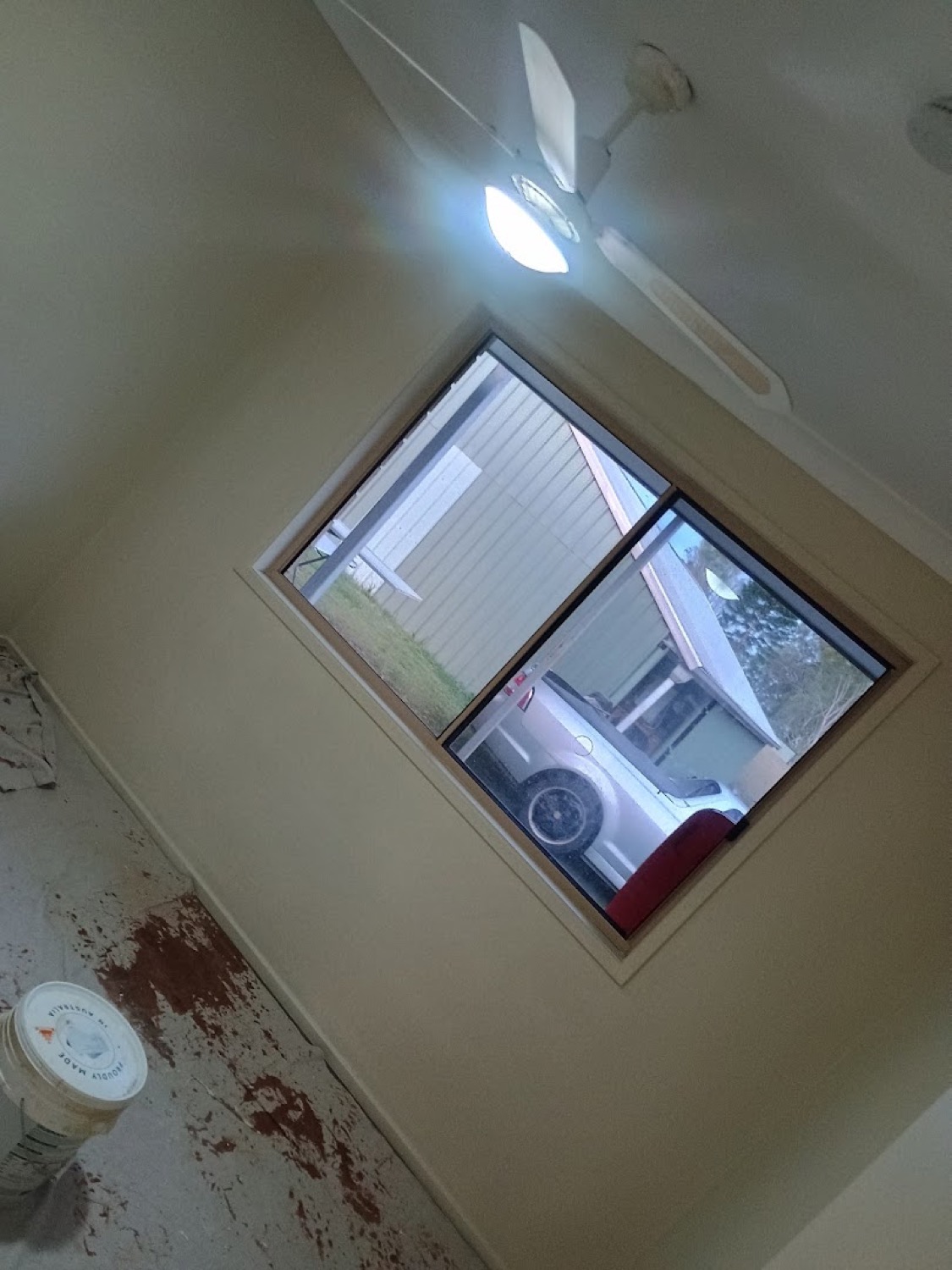 A window opening in a wall with fresh plaster patched around the frame