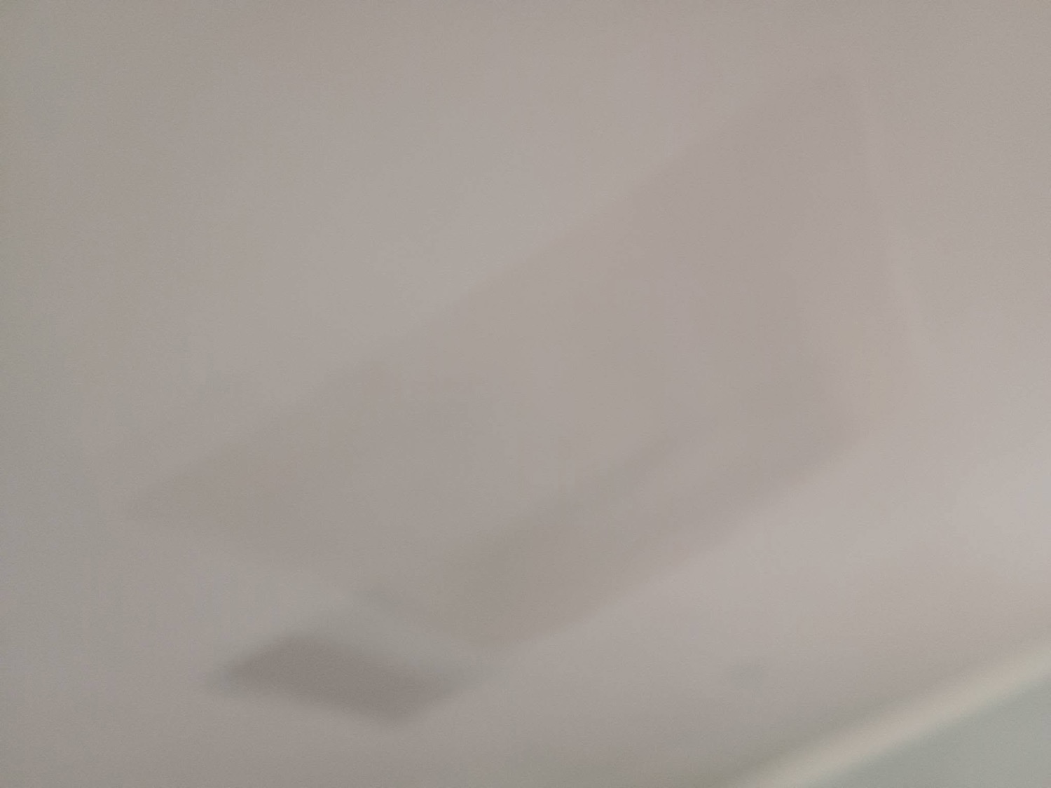 A finished plastered wall meeting the ceiling in a corner of a room